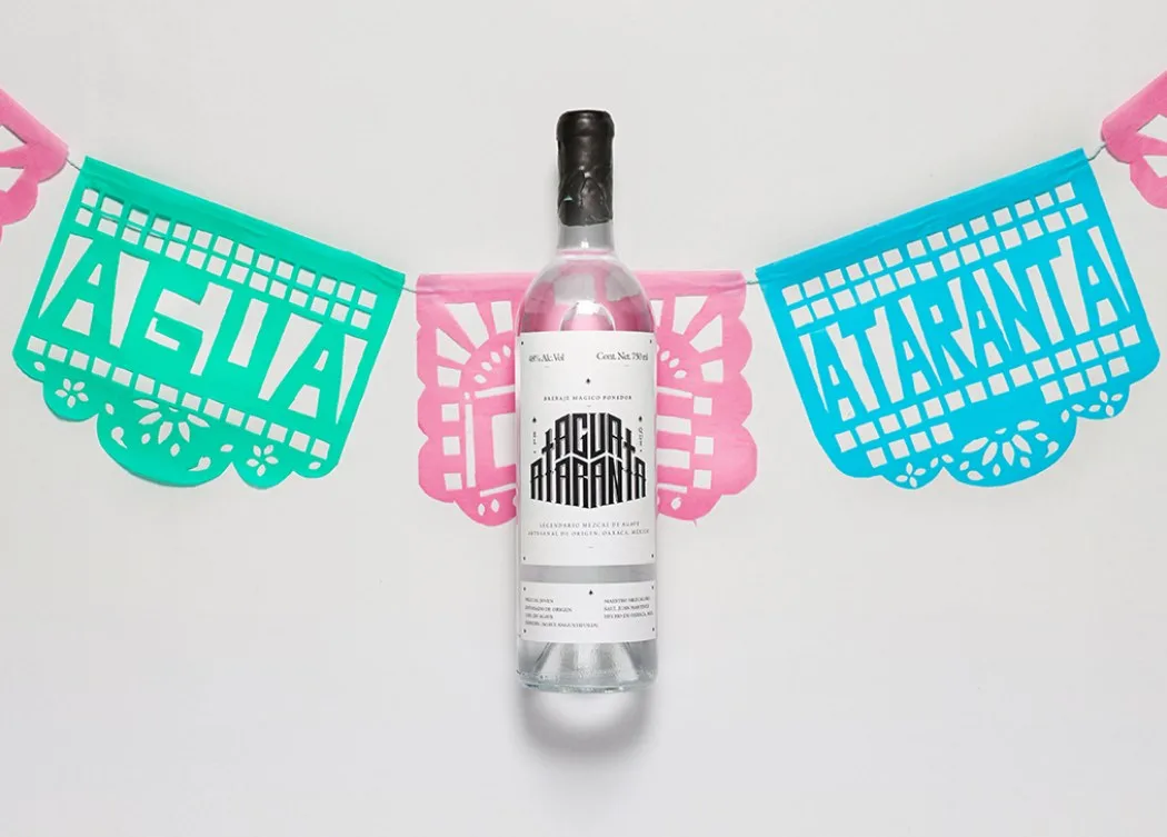 Klare Flasche zwischen türkisen und pinken Papiergirlanden