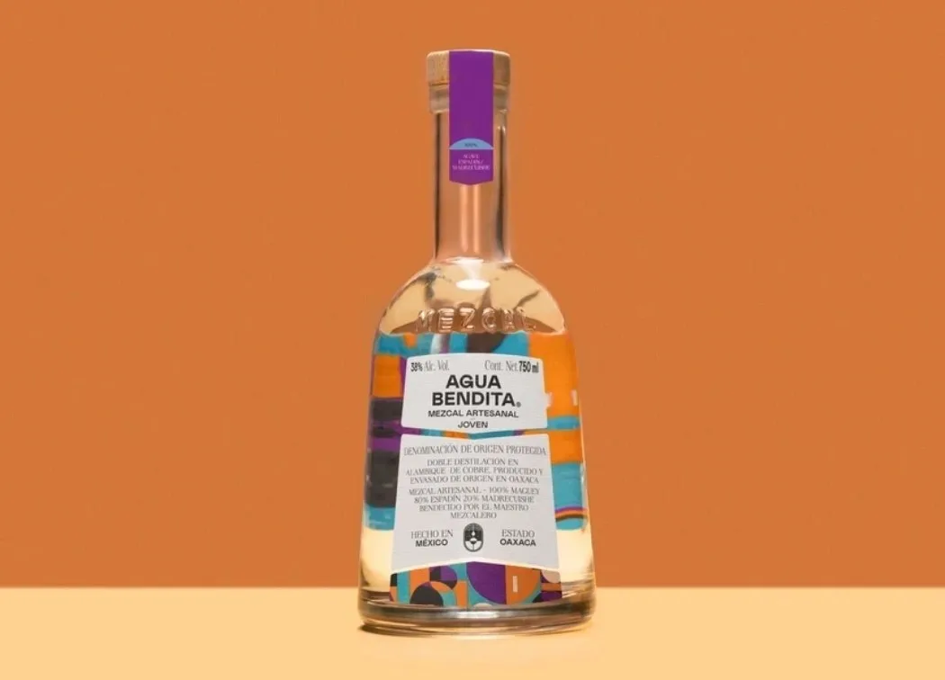 Mezcalflasche mit buntem Etikett vor orangem Hintergrund