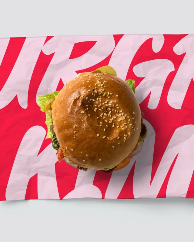 Burger auf rosa-rotem Papier mit grossem Schriftzug