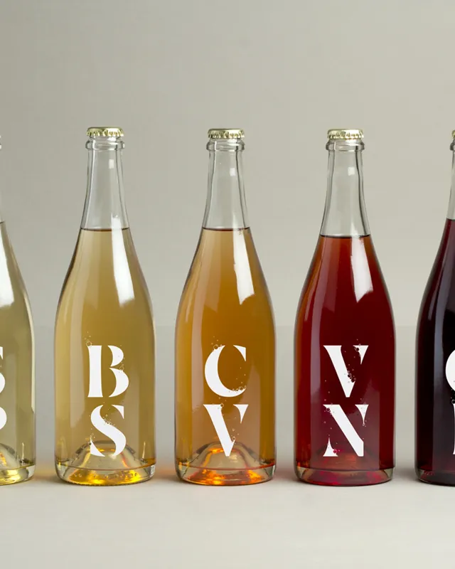 Fünf Flaschen in Weiss, Rosé und Rot mit grossen weissen Buchstaben